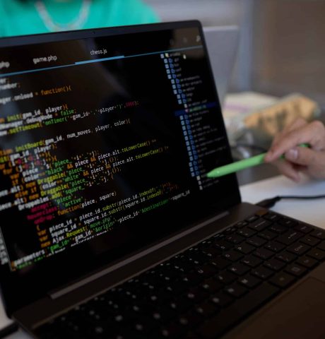 Focus on laptop screen with coded data and pen held by hand of young man Focus on laptop screen with coded data and pen held by hand of young male teacher or student making presentation of new software